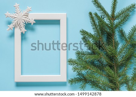 White frame with decoration snowflake and green spruce branch on blue background. Concept Merry christmas or Happy new year. Top view Flat lay Mockup Template for your design, card, invitation