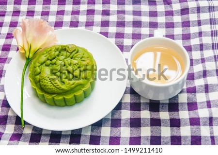 Food photography, top down view Closeup picture of sticky rice, matcha moon cake on a white plate with decorative flower and a cup of ginger tea. This is a traditional mid autumn snack