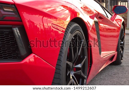 The passenger side of a red exotic car at sunset. Royalty-Free Stock Photo #1499212607