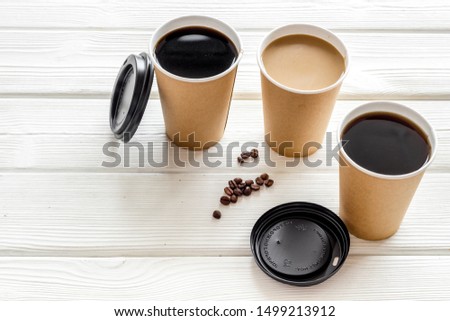Coffee to-go on white wooden background. Translation of the Russian text on the lid is Caution: contents hot.