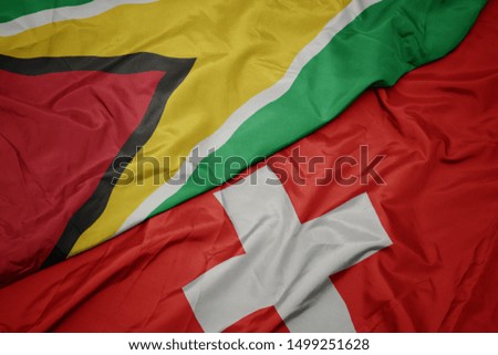 waving colorful flag of switzerland and national flag of guyana. macro