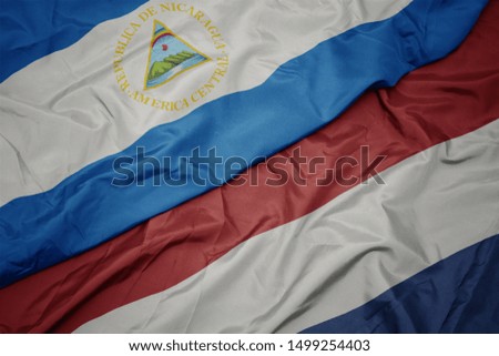 waving colorful flag of netherlands and national flag of nicaragua. macro