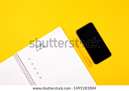 Notebook witn phone on a yellow background, top view, plans for 2020, year results, yellow pen, stylish background for your design.