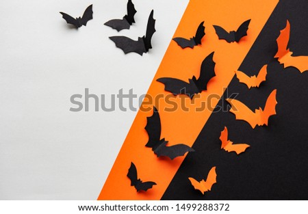 halloween  concept - black and orange paper bats flying over black and orange background