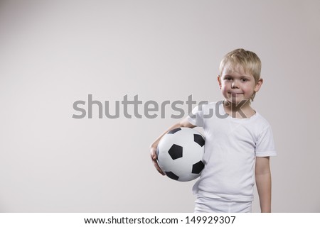 Portrait of a little boy holding soccer ball against white background