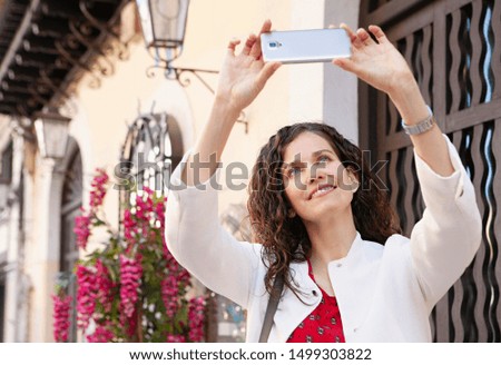 Portrait of beautiful smart tourist woman on city break vacation picturesque street sightseeing, using smartphone to take pictures, outdoors. Cultural travel technology, leisure recreation lifestyle.