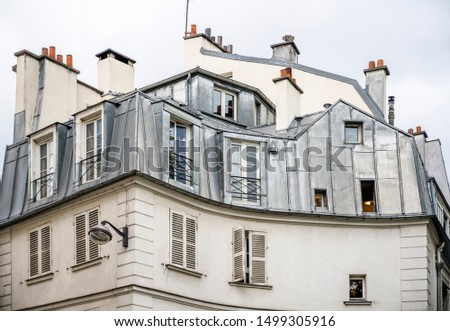 Rounded corner of residential apartments multi-storey house with wooden shutters and residential attic and balconies outside the windows located on one of the streets of Paris with old buildings