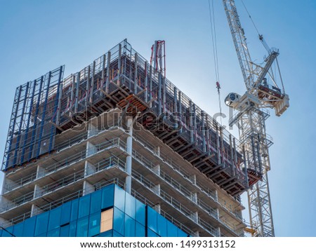 Building and construction scene. Heavy machinery lifting up materials. Blue sky, real estate development. Royalty-Free Stock Photo #1499313152