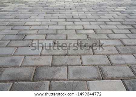 Low angle closeup of old pedestrian pavement surface paved with gray stone bricks