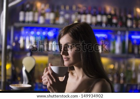 Closeup of a thoughtful young woman drinking tea at a recreational bar