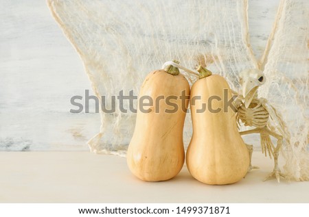 holidays image of Halloween. Pumpkins and bird skeleton over white wooden table