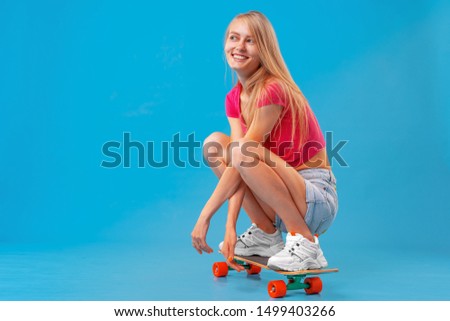 Pretty happy woman casually dressed sits on her skateboard 