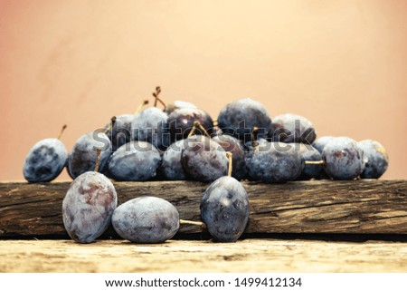 Beautiful fresh blue plums on old oak wooden table and brown wall background.