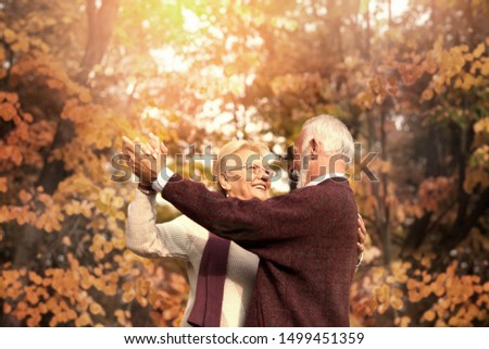 Cute elderly couple dancing in autumn day