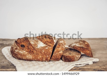Brown fresh bread with seeds are cut into pieces on old wood background. Copy, empty space for text