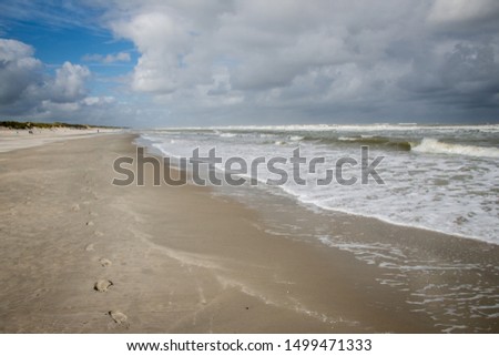 A walk along the beach in a stormy weather with a high tide in summer in Ameland, leaving footprints