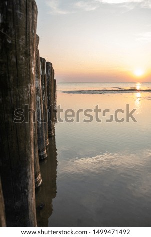 Columns of wooden posts at the beach pictured at sunset