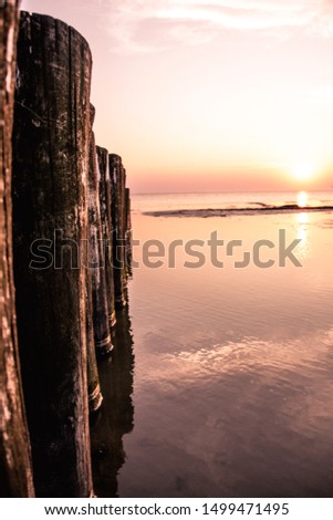 Columns of wooden posts at the beach pictured at sunset