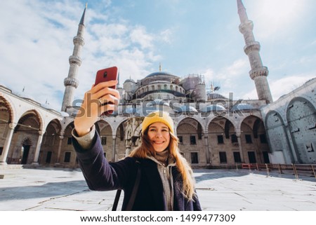 Young european woman takes a selfie portrait in Istanbul, Turkey. girl walks through winter istanbul. blonde takes a photo on the phone against the background of a mosque in autumn day.