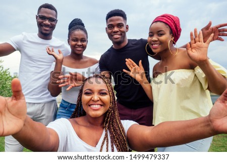 group of five friends female and male taking selfie on camera smartphone and having fun outdoors lifestyle near lake Royalty-Free Stock Photo #1499479337