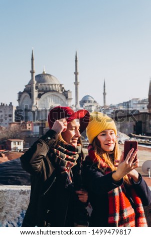 Girlfriends take a selfie on the roof of the Grand Bazaar, Istanbul, Turkey. Two smiling girls are photographed on the phone against the background of Istanbul on a clear winter day.
