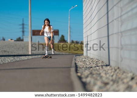 stylish girl in white stockings ride on longboard down the street and listening music.