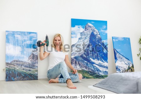 girl hangs a large photo canvas at home
