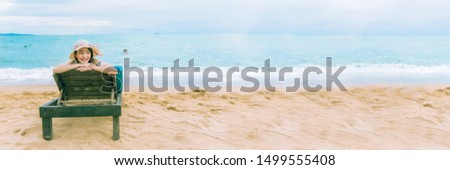 Happy summer holiday vacation on the seaside beach, Traveller tourist woman with hat enjoying and relaxing on the chair at Pataya beach, Thailand, panorama shot for banner. Royalty-Free Stock Photo #1499555408