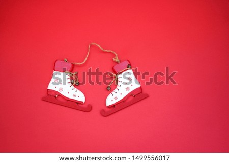 white wooden toy handmade made skates, close-up on a red background. winter holidays concept.