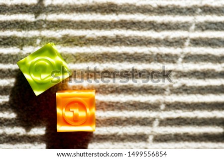 two colored children's cubes lie on the floor, they are illuminated by the light from the window through the blinds. sad picture about childhood. copy space.