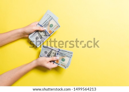 Top view of female hand giving some money, Close-up of counting one hundred dollar bills. Business concept on colorful background.
