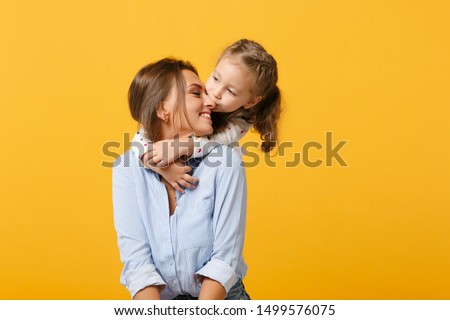 Woman in light clothes have fun with cute child baby girl 4-5 years old. Mommy little kid daughter isolated on yellow background studio portrait. Mother's Day love family parenthood childhood concept Royalty-Free Stock Photo #1499576075