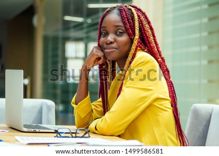 woman fashion designer with afro pigtails dreadlocks working on her atelier or print publishing house. cosmetic distributor working in the office.