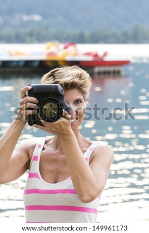 Young woman W34 on vacation takes a picture with her DSLR