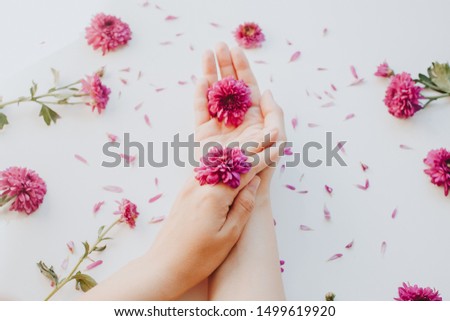 Close up photo of female hands with deep pink  flowers on white background. Natural cosmetic  beauty and skincare concept.