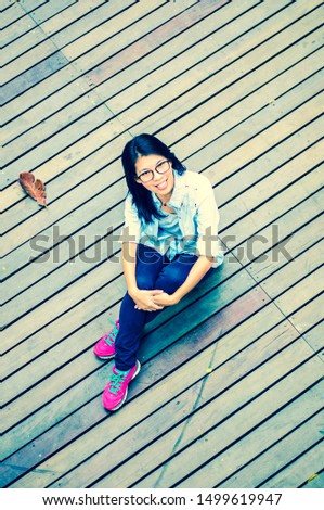 A cute Asian girl sitting on the wooden floor and happily smiling for relax time.