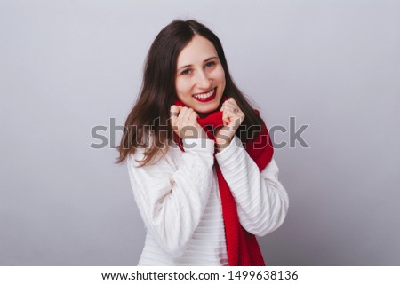 Photo of young woman, in red scarf doig pretty eyes, over isolated background