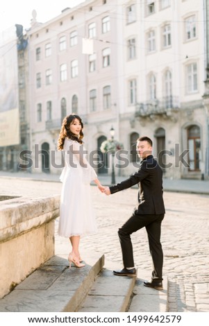 Beautiful stylish Asians couple man and woman walking on the summer streets of old European city