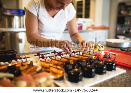 Young woman decorating raspberry cookies in her home,stock photo