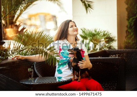 A girl in red pants and with a small black dog