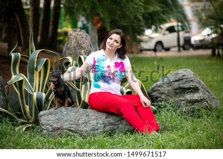A girl in red pants and with a small black dog