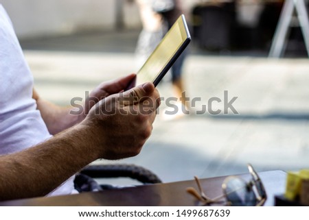 Male hand with black tablet on bright blurred background. Close up,man hands touching digital tablet computer connecting WiFi,browsing internet while working at modern restaurant,communication concept