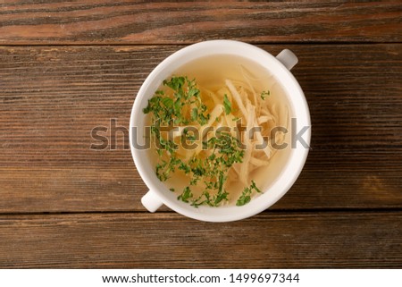 Stock with noodles and white meat on wooden