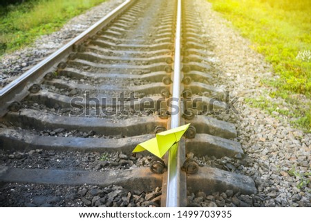 Yellow handmade paper plane lying on the rail tracks. Freedom concept photo.Travel lifestyle motivation. Railway train transport industry.