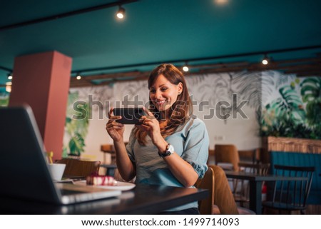 Portrait of a happy young woman taking picture of delicious cake on a plate.