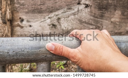 male hand holding steel bar and thumb point out with wooden back