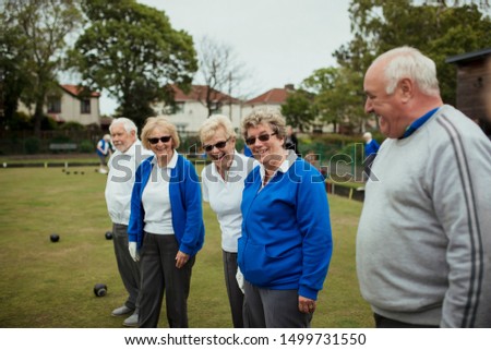 A side view shot of a group of seniors smiling in a bowling green.