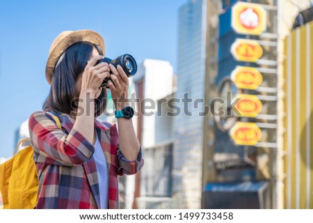 Woman photographer is taking images with dslr camera. Photographer covering her face with the camera. Happy woman on vacation photographing with a dslr camera in the city. Vacation photography travel