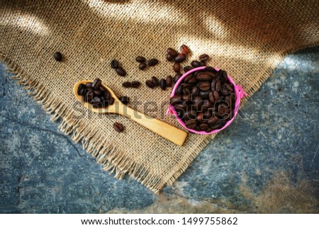 Roasted coffee beans in a pink zinc bucket on a sackcloth background.