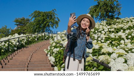 Woman takes selfie on phone with white Hydrangea flower garden 
